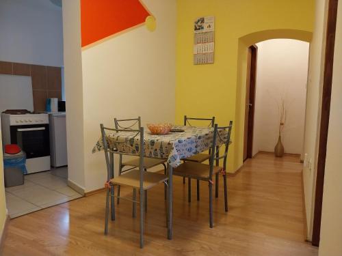 a dining room table with four chairs and a kitchen at Apartmani Jadran in Mali Lošinj