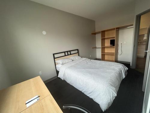 1 dormitorio con cama blanca y mesa de madera en Residence & Conference Centre - Brampton, en Brampton