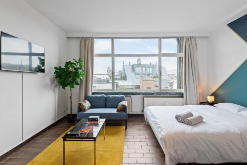 een slaapkamer met een bed, een bank en een raam bij Cozy Antwerp - Cityview Studio FREE PARKING in Antwerpen