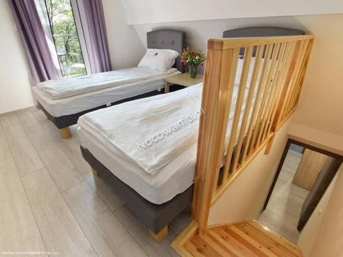 two twin beds in a room with a staircase at Lawendowa Przystań in Wielen Zaobrzanski