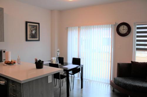 a kitchen and living room with a table and a clock at Modern Town House Barrie South in Barrie