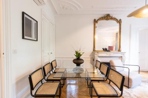 une salle à manger avec une table en verre, des chaises et un miroir dans l'établissement Sweett - Maison Wagram, à Paris