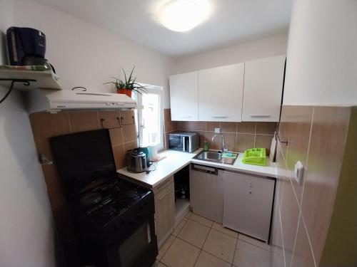 a small kitchen with white cabinets and a black stove at Apartmani Jadran in Mali Lošinj