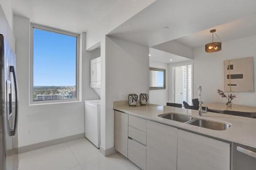 a white kitchen with a sink and a large window at Stunning Beach Resort Large 4BR 3BA Condo 24 FL in Hallandale Beach