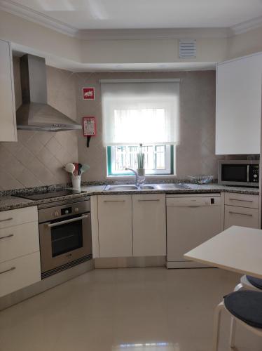 a kitchen with white cabinets and a sink and a window at Casa Brisa do Mar in Porches