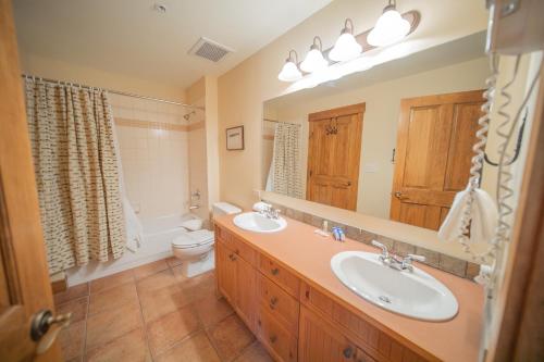 a bathroom with two sinks and a toilet and a mirror at Springs 8909 in Keystone