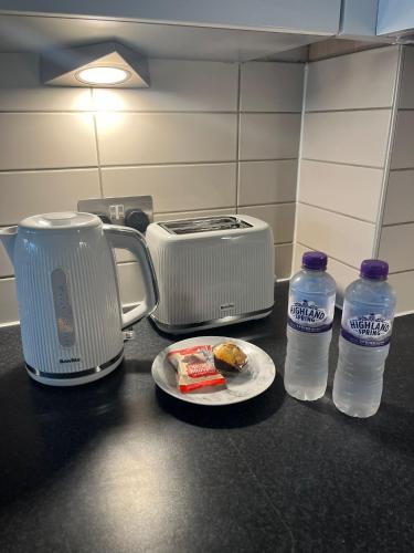 a counter with a toaster and a plate of food and water at Pettit Apartments - Central "Free Parking" in Liverpool