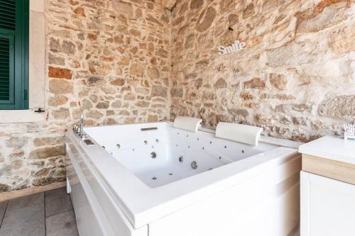a white bath tub in a bathroom with a stone wall at Holiday house with a swimming pool - Villa Melavita in Stari Grad