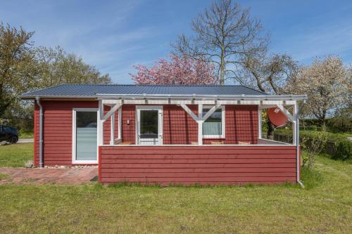 a red house with a roof on a yard at Holtdeel in Gelting