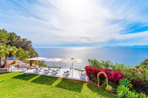 a backyard with chairs and umbrellas and the ocean at Villa Bay Blue by PriorityVillas in Badia Blava