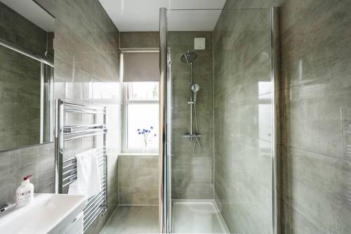 ein Bad mit einer Dusche und einem Waschbecken in der Unterkunft Newly Renovated Modern 4 Bed 3 Bath Apartment London in London
