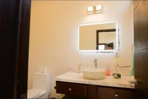 y baño con lavabo, aseo y espejo. en Casa Tikal cerca de aeropuerto, en Flores