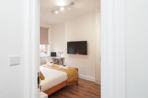 a bedroom with a bed and a flat screen tv at Newly Renovated Modern 4 Bed 3 Bath Apartment London in London