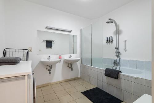 a bathroom with two sinks and a shower and a tub at Cozy Antwerp - Cityview Family Apartment FREE PARKING in Antwerp
