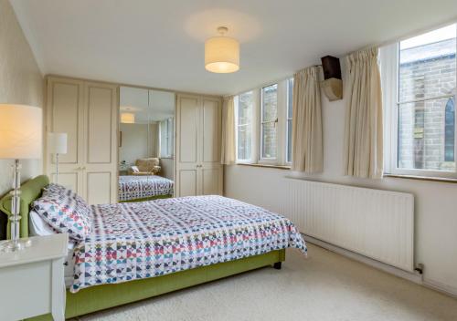 a bedroom with a bed and a mirror and windows at Humbug Lodge in Pateley Bridge