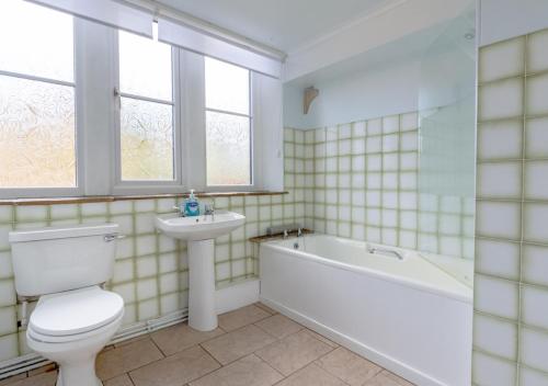 a bathroom with a tub and a toilet and a sink at Humbug Lodge in Pateley Bridge