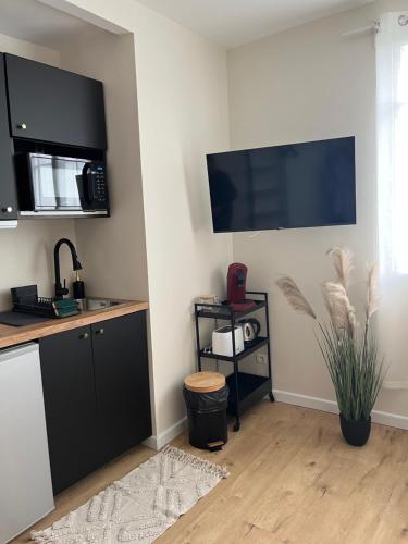 eine Küche mit einem schwarzen Schrank und einem TV an der Wand in der Unterkunft Appartement plein centre ville d’Alfortville in Alfortville