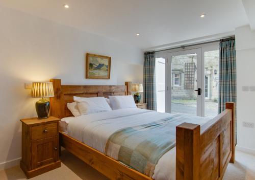 a bedroom with a large wooden bed and a window at Mullions Nook in Buckden