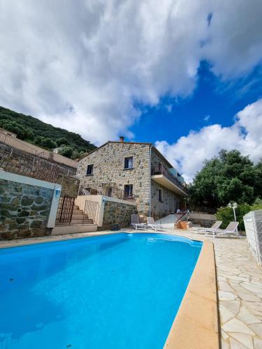 une grande piscine bleue devant un immeuble dans l'établissement Hôtel Villa Les Orangers, à Olmeto