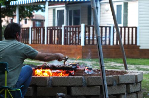 Ein Mann, der Essen über einem Feuer im Garten kocht. in der Unterkunft Del Falco AgriCamp-12 kilometers to Garda Lake and Verona in Bussolengo