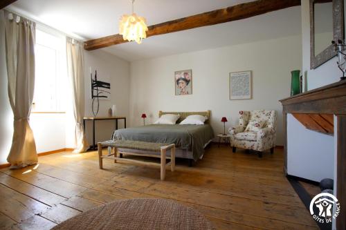 ein Schlafzimmer mit einem Bett, einem Sofa und einem Stuhl in der Unterkunft Le Bila in Troncens