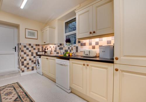 a large kitchen with white cabinets and a window at The Old Grammar School in Hawes