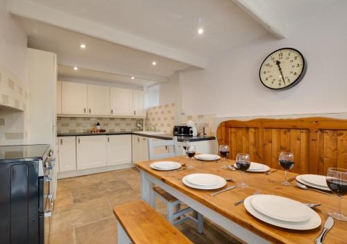 a kitchen with a wooden table and a clock on the wall at Mary End in Hawes