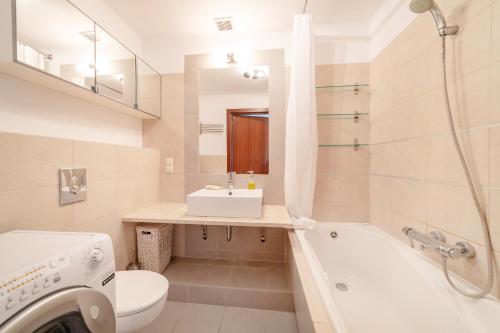 a bathroom with a tub and a sink and a toilet at Nowoczesny Apartament w Helskiej Villi w Helu in Hel