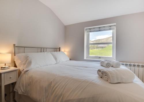 a bedroom with a white bed with towels on it at Ghyllfoot Apartment in Gunnerside