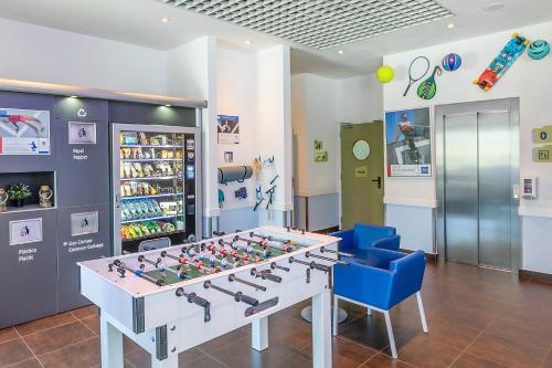 a game room with a foosball table and blue chairs at Hotel ibis Budget Porto Gaia in Vila Nova de Gaia