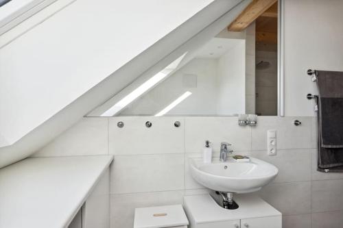 ein weißes Badezimmer mit einem Waschbecken und einem Spiegel in der Unterkunft Wohnung in Baddeckenstedt mit Balkon & Aussicht in Baddeckenstedt