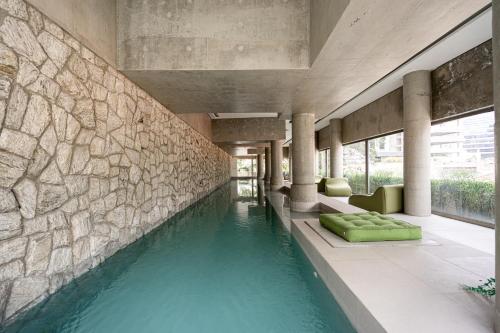 a swimming pool in a building with a stone wall at Tabas - VN Ferreira Lobo in São Paulo