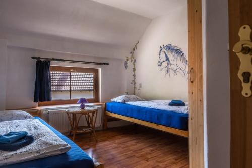 a bedroom with two beds and a painting of a horse on the wall at Ranč Červený mlýn in Lisov
