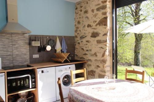 - une cuisine avec une table et un lave-linge dans l'établissement Les Renardières, à Sussac