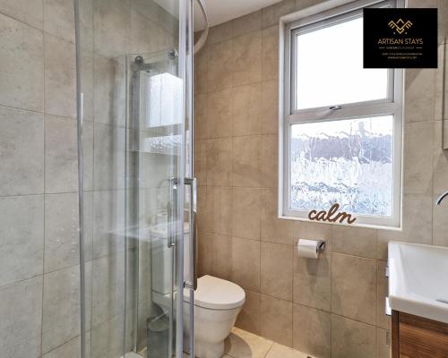 a bathroom with a shower and a toilet and a window at Stunning Tropical Oasis By Artisan Stays I Free Parking I Weekly or Monthly Stay Offer I Sleeps 7 in Southend-on-Sea