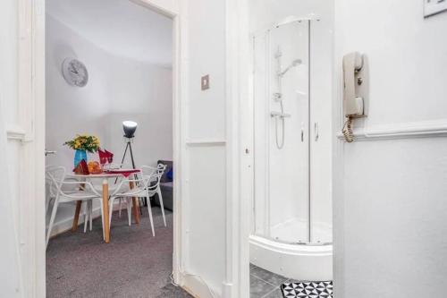 a bathroom with a shower and a dining room with a table at Lovely Entire Flat in Kings Cross in London