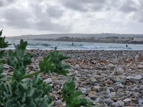a rocky beach with people surfing in the ocean at Hotel Portofina in Santa Marinella