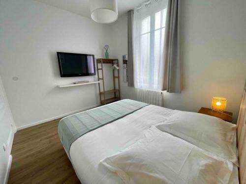a bedroom with a bed and a flat screen tv at L’Accostage in Dieppe