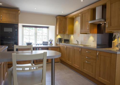 a kitchen with wooden cabinets and a table and chairs at Throstle Nest House in Gunnerside