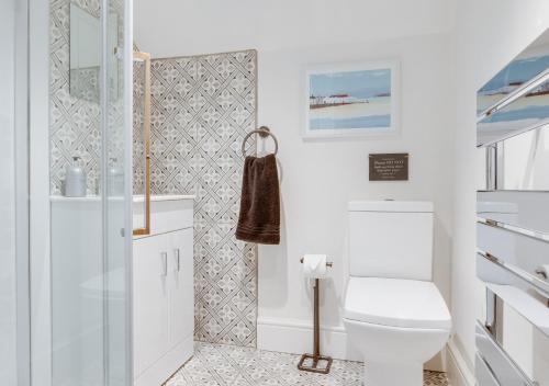 a white bathroom with a toilet and a shower at 1 Browcote Cottage in Ravenscar