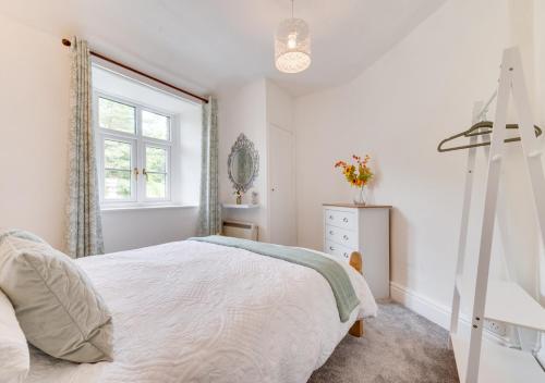 ein weißes Schlafzimmer mit einem Bett und einem Fenster in der Unterkunft 2 Moorcock Cottages in Cotterdale
