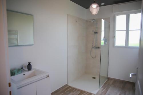 La salle de bains blanche est pourvue d'une douche et d'un lavabo. dans l'établissement La Huchetiere, à Droué