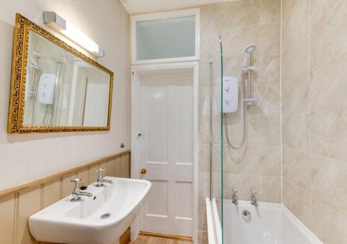a bathroom with a sink and a tub and a mirror at 2 Moorcock Cottages in Cotterdale