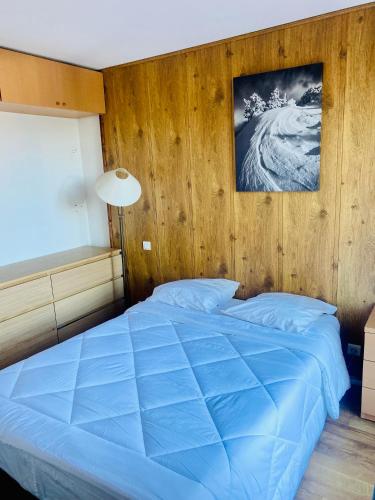 - une chambre avec un lit bleu et un mur en bois dans l'établissement Font-Romeu : T2 avec grande terrasse et garage, à Font-Romeu-Odeillo-Via