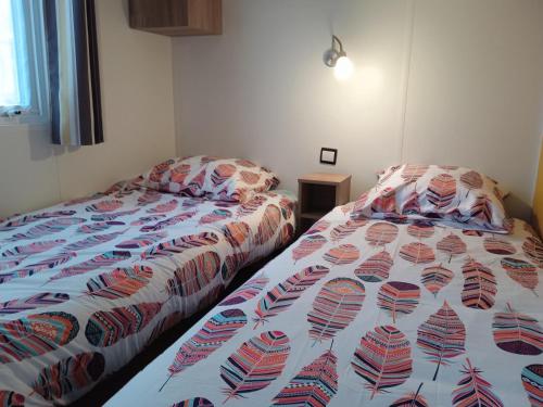 a bedroom with a bed with a comforter on it at MOBIL-HOME 6-8 pers, Domaine de Kerlann 4* in Pont-Aven