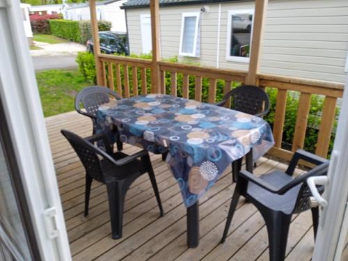 a table and chairs on a deck with a table cloth at MOBIL-HOME 6-8 pers, Domaine de Kerlann 4* in Pont-Aven