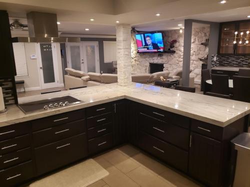 a kitchen with black cabinets and a living room at Luxury Villa, with bonus pool house, Private Pool, Hot tub, rock water fall and slide, putting green, basketball, shuffle board, play gym, privately gated on circular driveway. in Las Vegas