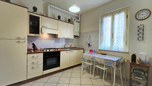 una cucina con armadi bianchi, tavolo e finestra di CASA OLTREPO silenziosa comoda centrale e parcheggio interno a Casteggio