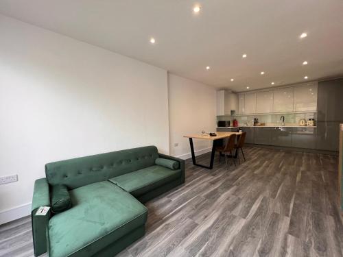 ein Wohnzimmer mit einem grünen Sofa und einem Tisch in der Unterkunft Star London Finchley Lane 3-Bed Residence with Garden in Hendon