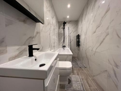 uma casa de banho branca com um lavatório e um WC em Star London Finchley Lane 3-Bed Residence with Garden em Hendon